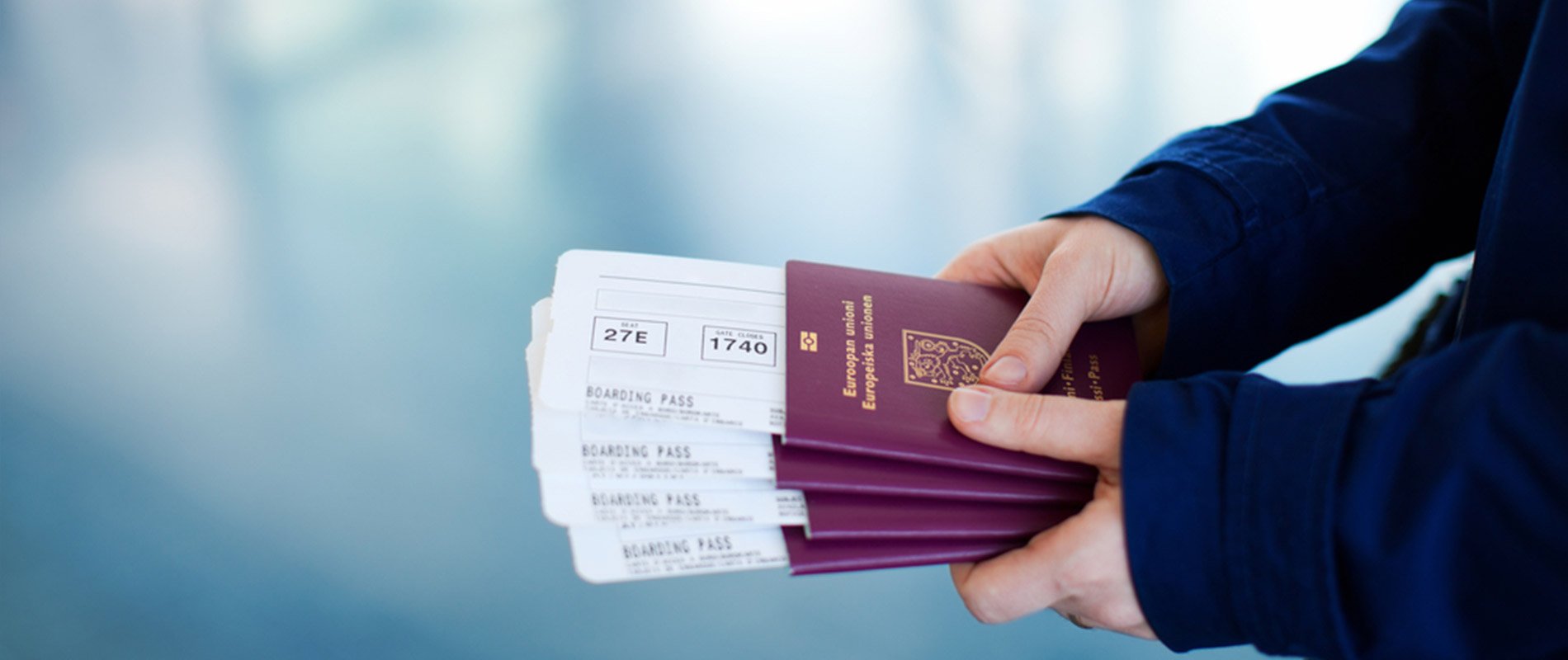  A hand holding a passport with flight tickets in front of blurred background representing the search query 'Documents for job application in foreign country'.